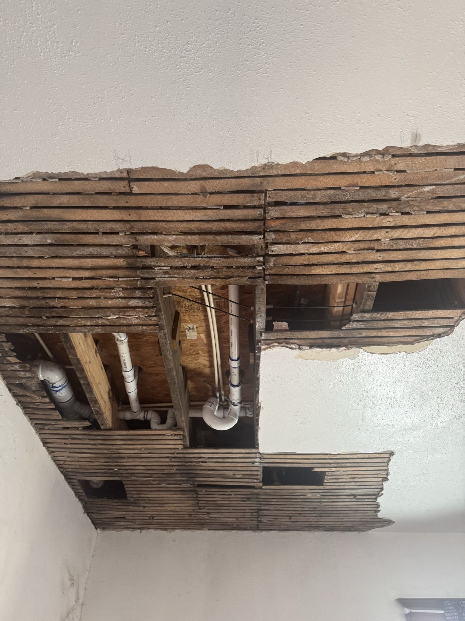 Collapsed ceiling with exposed wooden slats and hanging light fixtures in a room