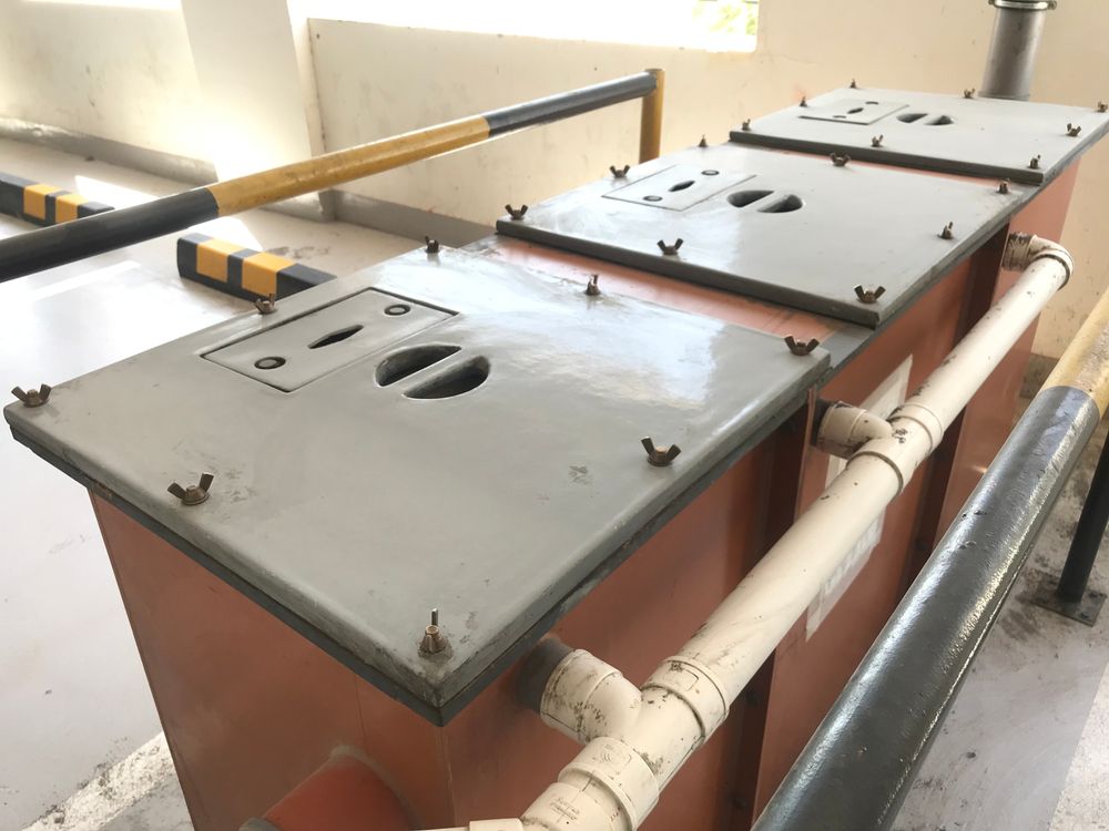 Large metal industrial machine with bolted gray lids and white pipes in a workshop