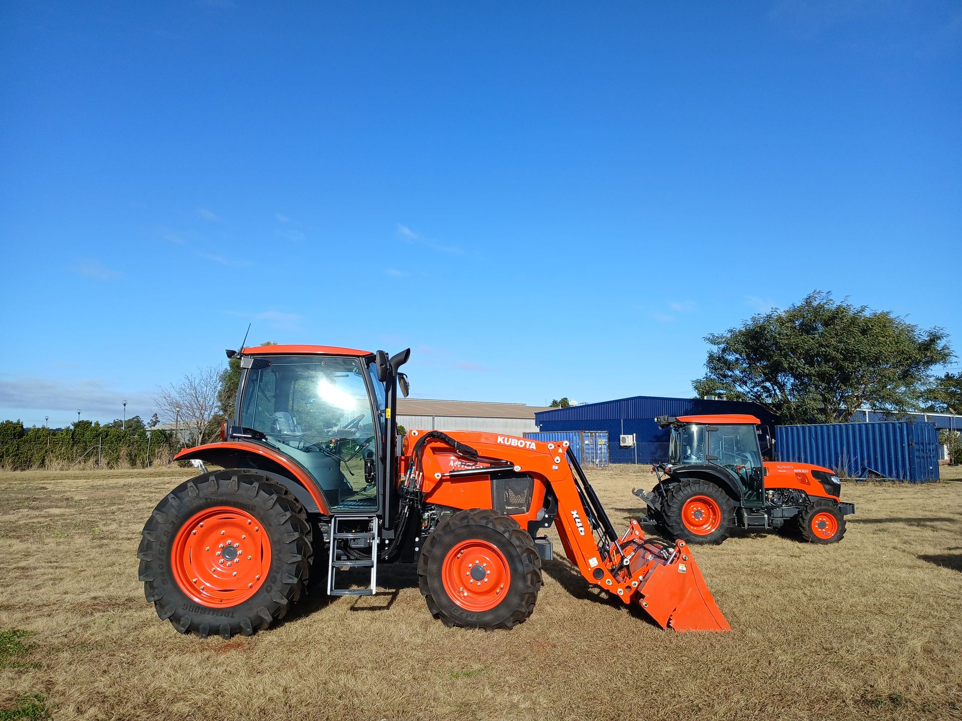 A Red Atv is Towing a Smaller Atv in a Dirt Field — Ken Mills Machinery in Kingaroy, QLD