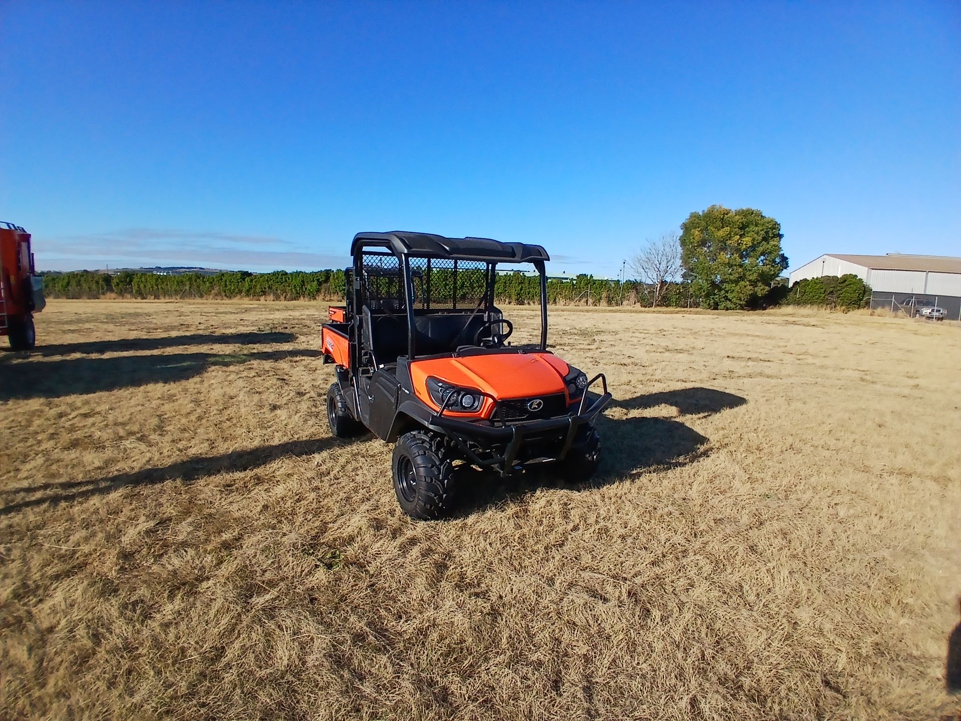 A Red Atv is Towing a Smaller Atv in a Dirt Field — Ken Mills Machinery in Kingaroy, QLD