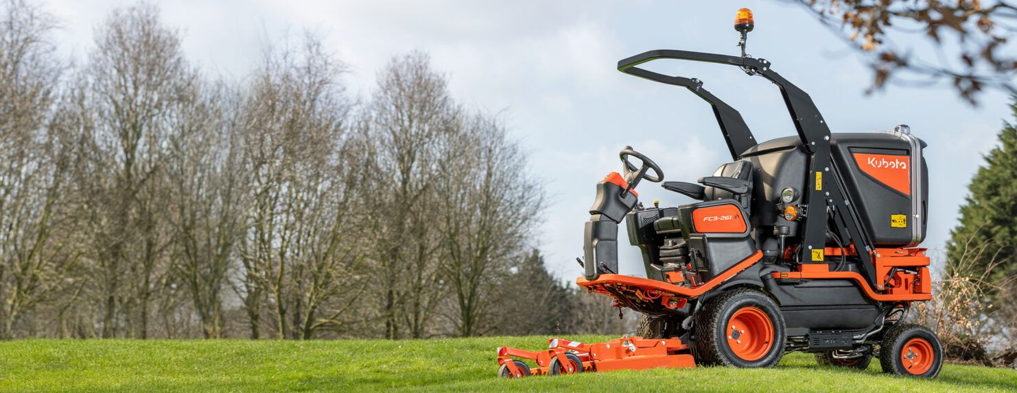 Orange Compact Tractor Mowing Grass in a Field — Ken Mills Machinery in Gayndah, QLD