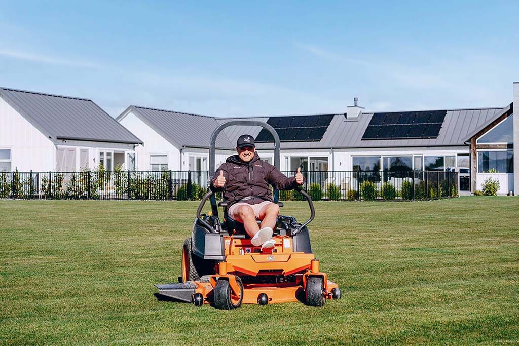 Person Riding an Orange Lawn Mower on a Grassy Lawn — Ken Mills Machinery in Eidsvold, QLD