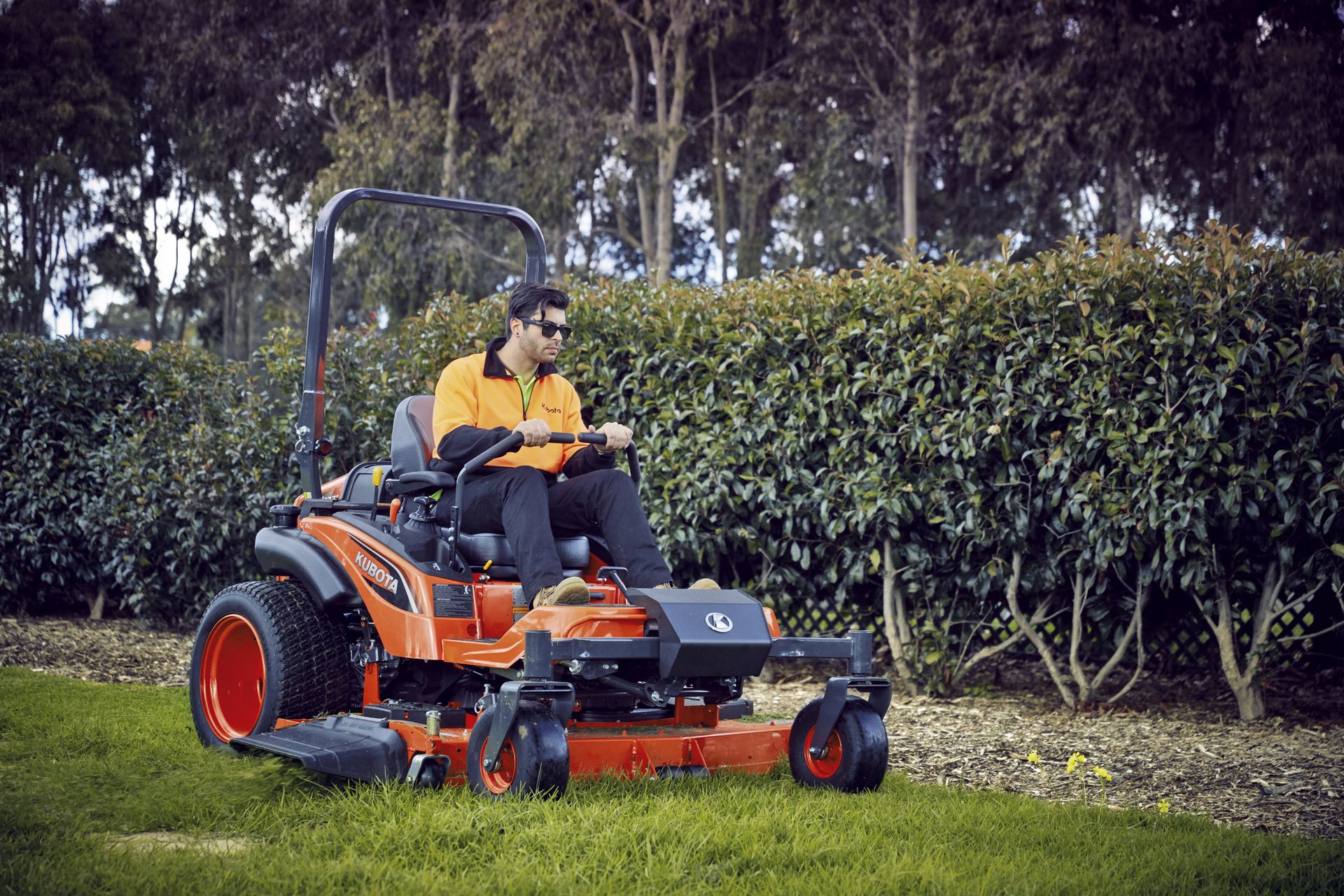 A man is riding a lawn mower on a lush green field. — Ken Mills Machinery in Kingaroy, QLD