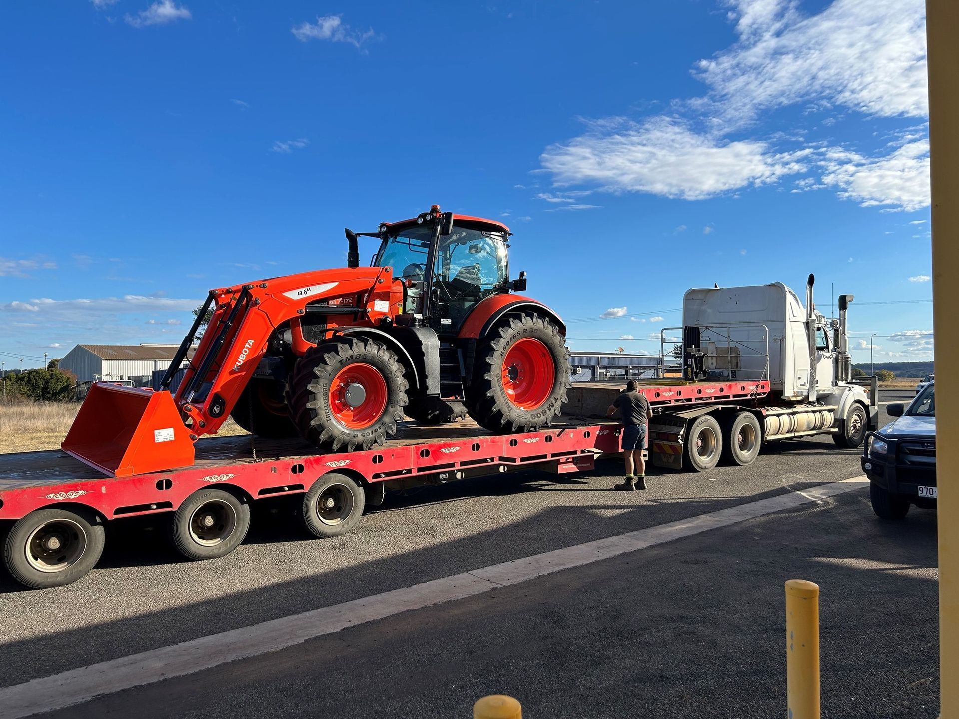 A tractor is being transported on a flatbed trailer. — Ken Mills Machinery in Kingaroy, QLD