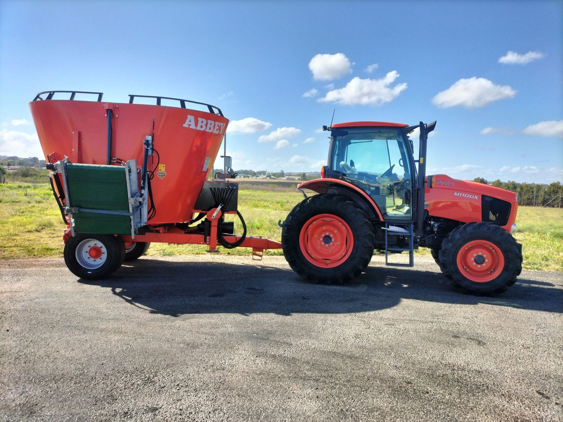 A tractor with a trailer attached to it is parked in a field. — Ken Mills Machinery in Kingaroy, QLD