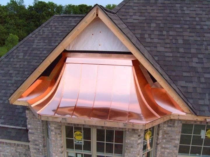 Copper awning over a dormer window on a gray shingled roof