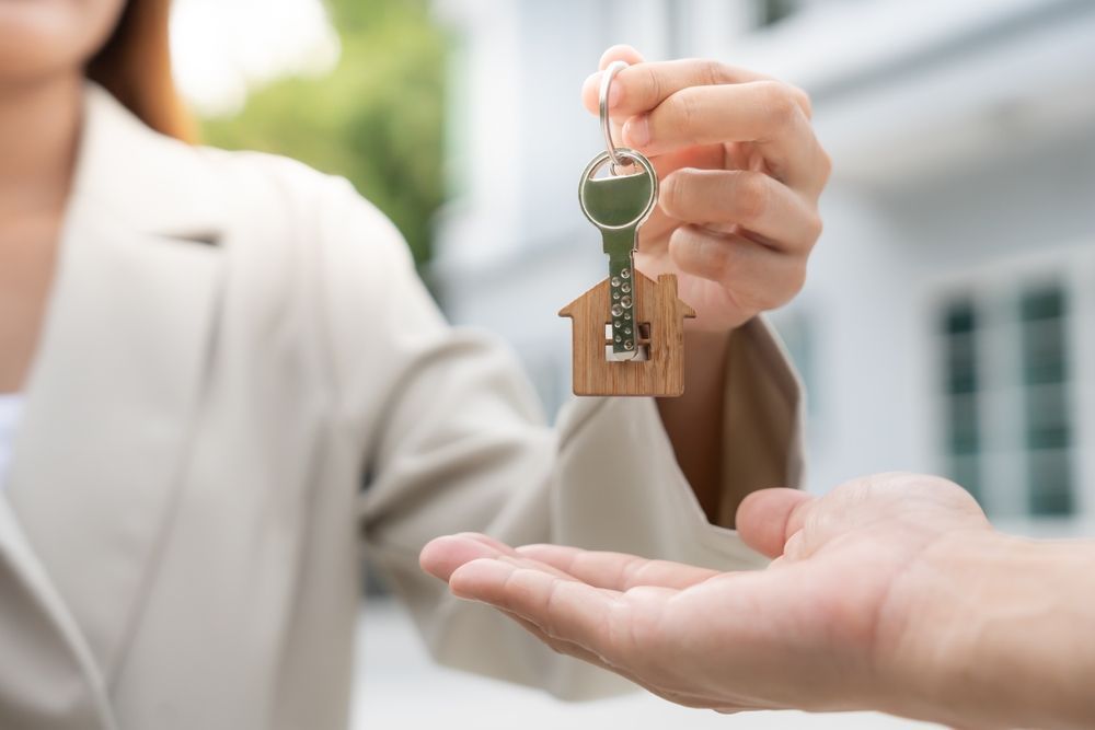 Handing over house keys into an open palm outside a home
