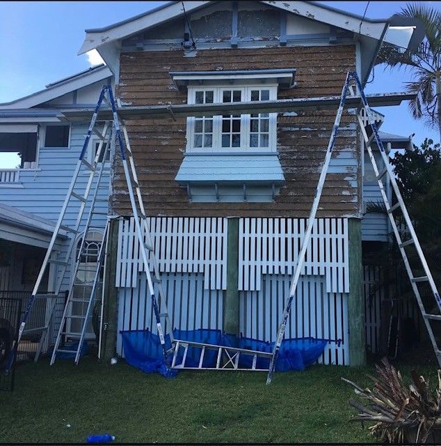 House under construction with multiple ladders and scaffolding on the front facade