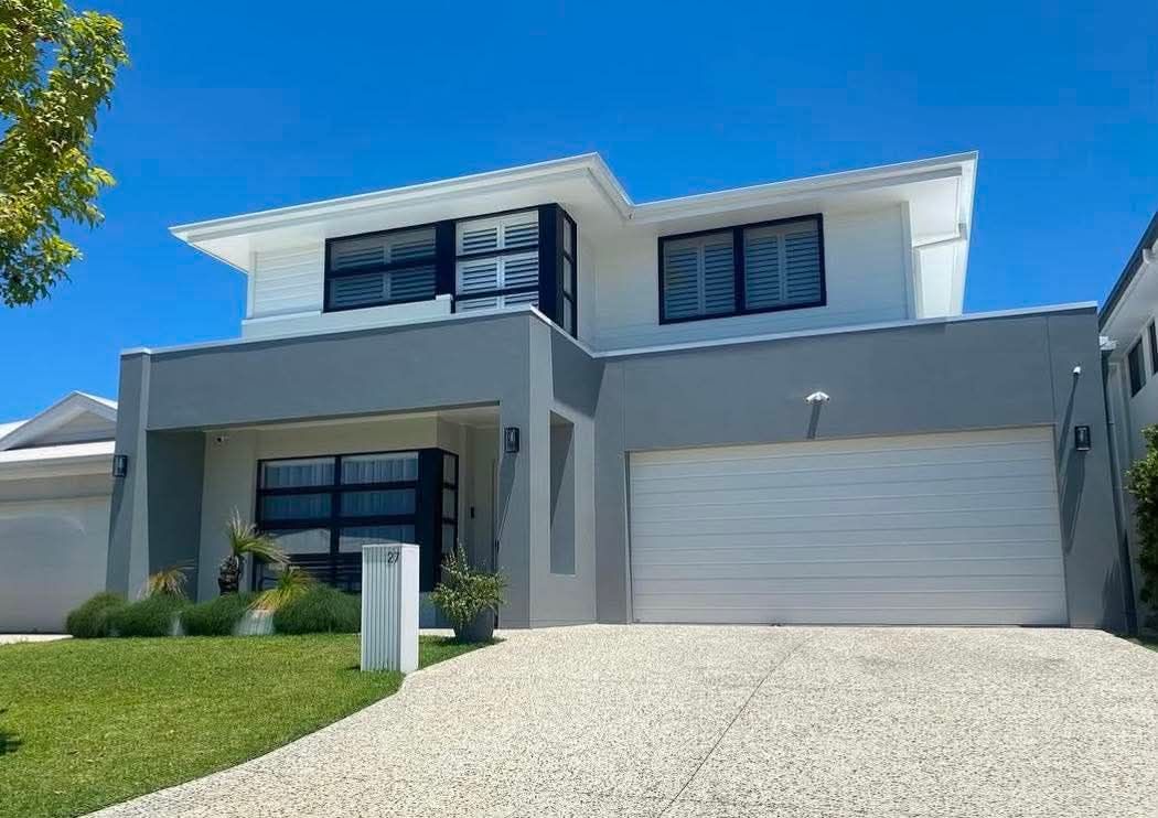 Modern two-story gray house with white garage door and blue sky