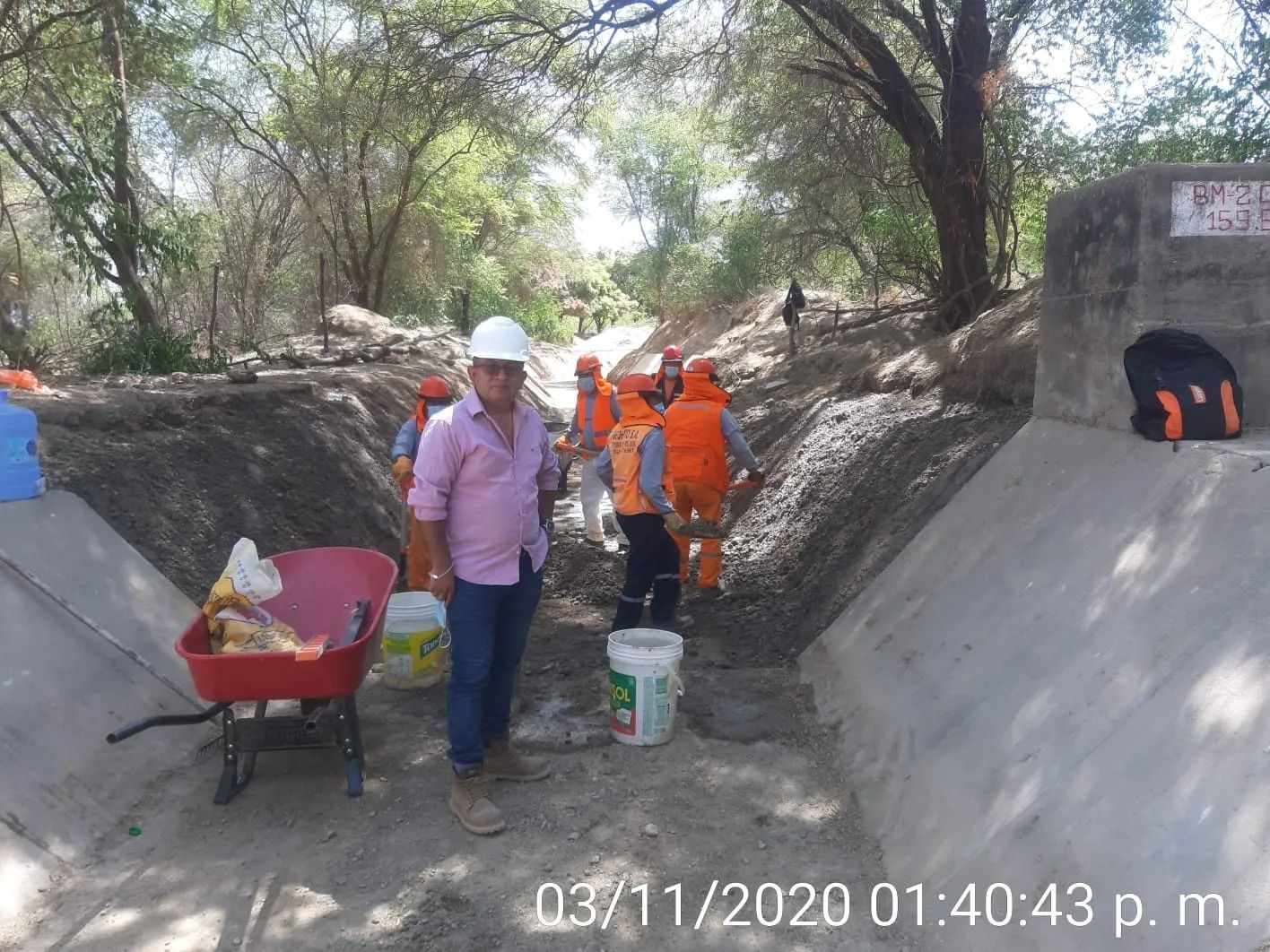 Trabajadores con trajes de seguridad naranjas en una zona boscosa rocosa