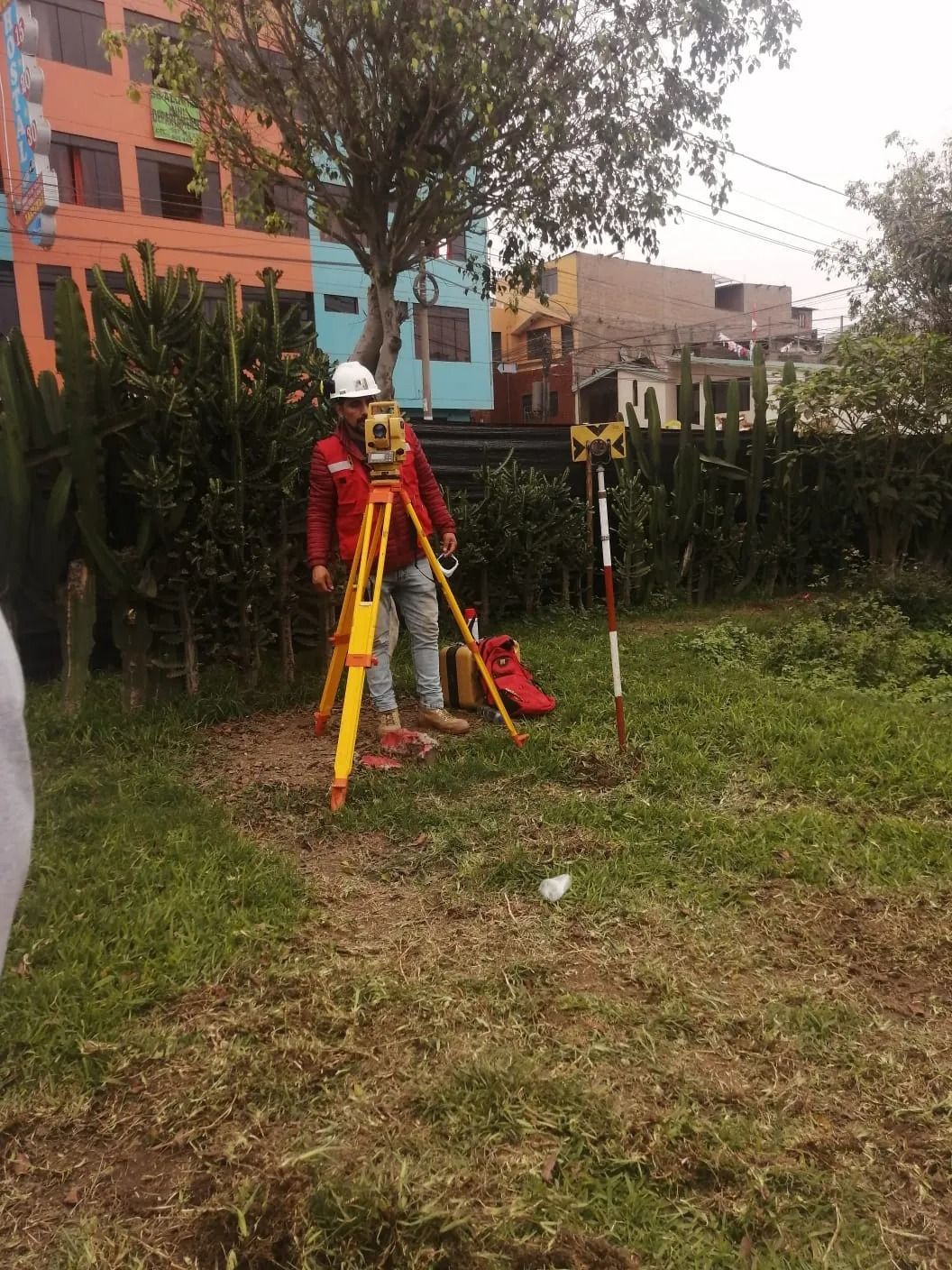 Un trabajador con equipo de seguridad utiliza material de topografía