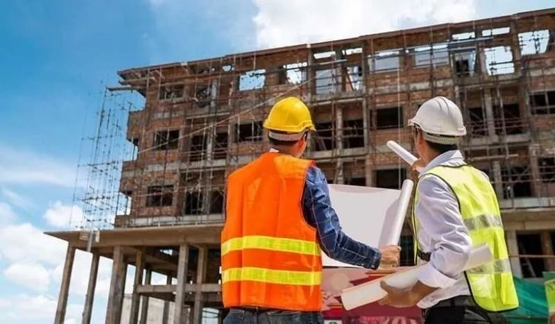Equipo de ingenieros de Constructora Niyaro revisando planos en obra con cascos y chalecos reflectivos