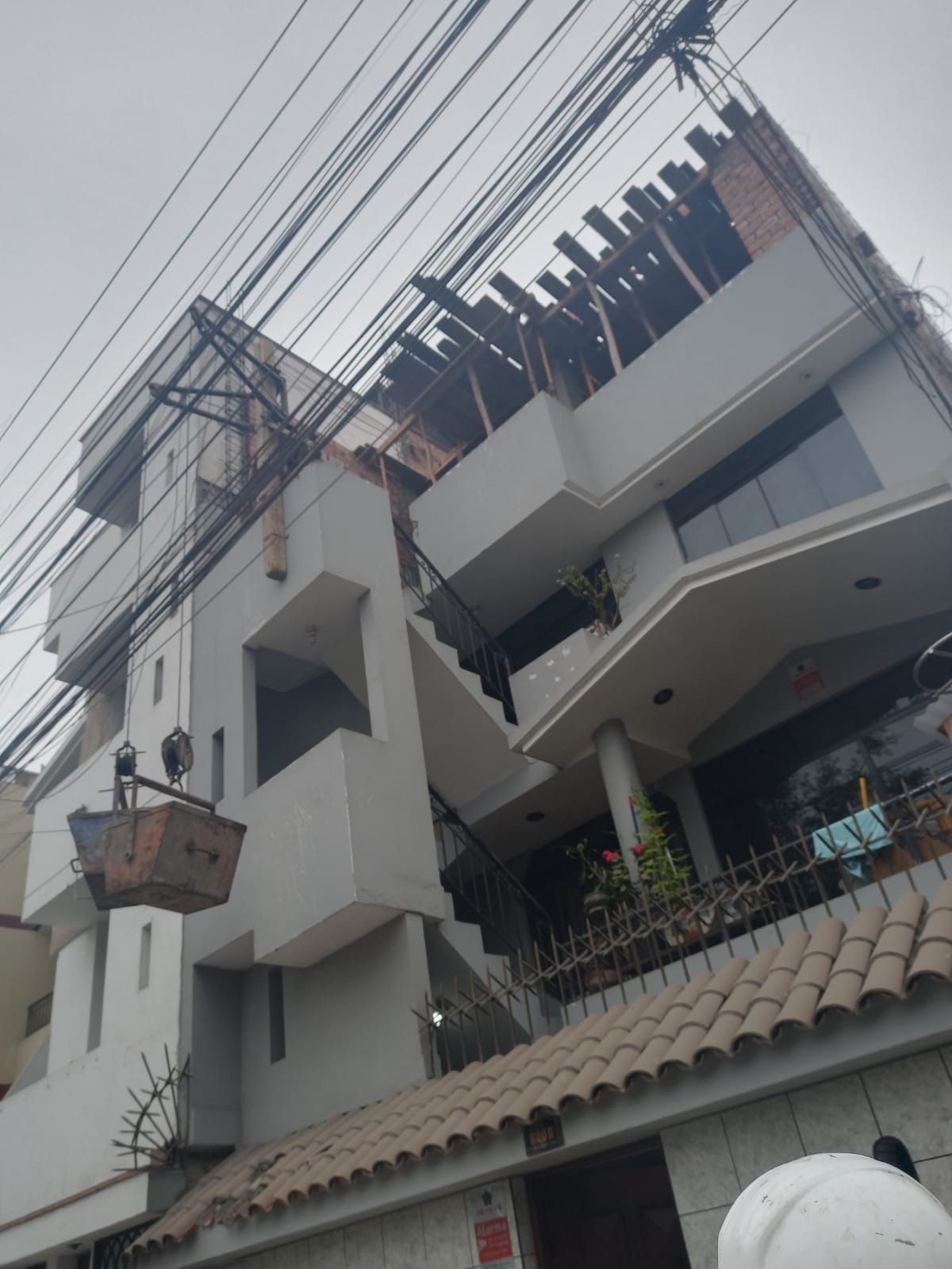 Edificio de apartamentos dañado con barras de refuerzo expuestas y pisos superiores agrietados en construcción o reparación.