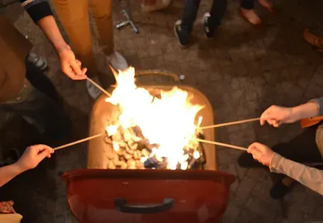 A group of people are roasting marshmallows over a fire.