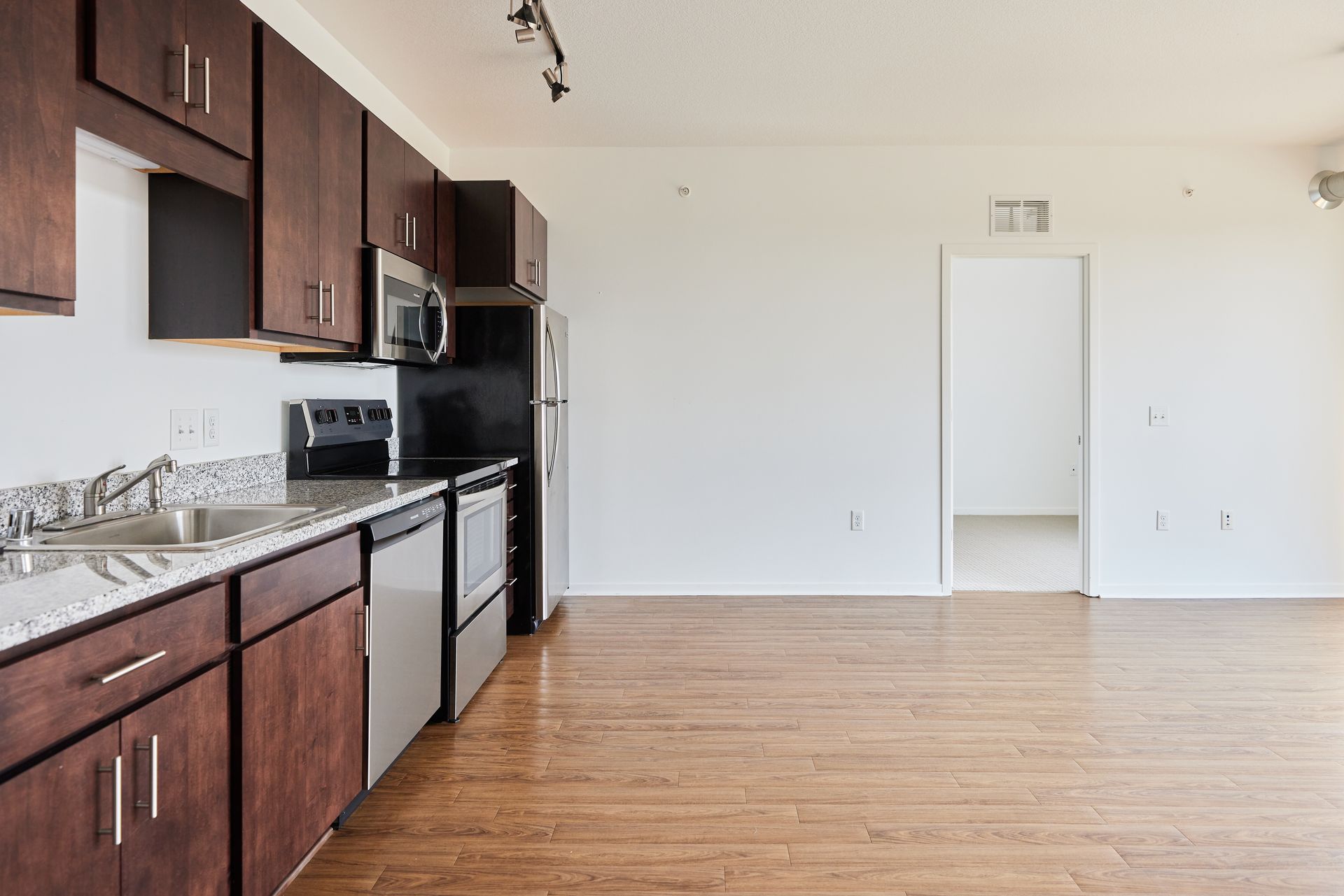 Kitchen with dark wood cabinets, stainless steel appliances, and hardwood floors at Southsider Apartments in Minneapolis, MN.