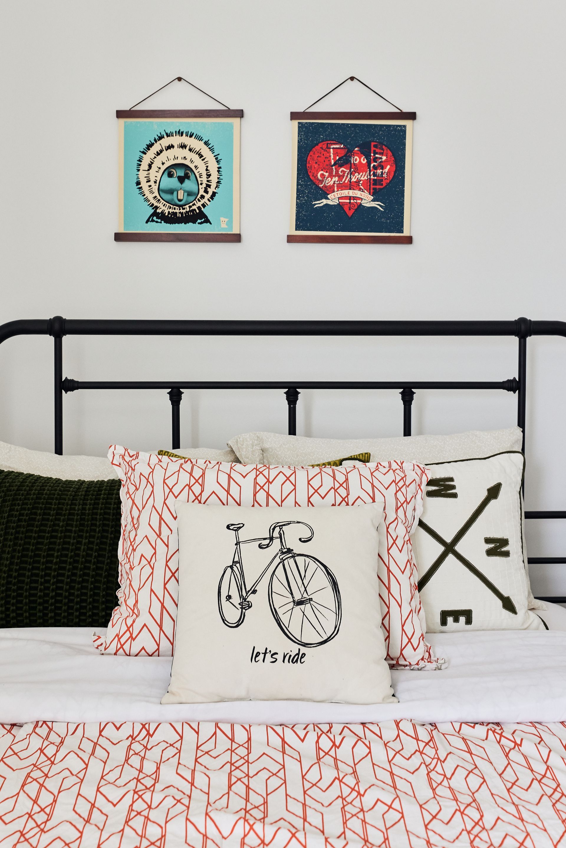 Bedroom with a black metal bed frame, decorative pillows, and two framed artworks above at Southsider Apartments in Minneapolis, MN.