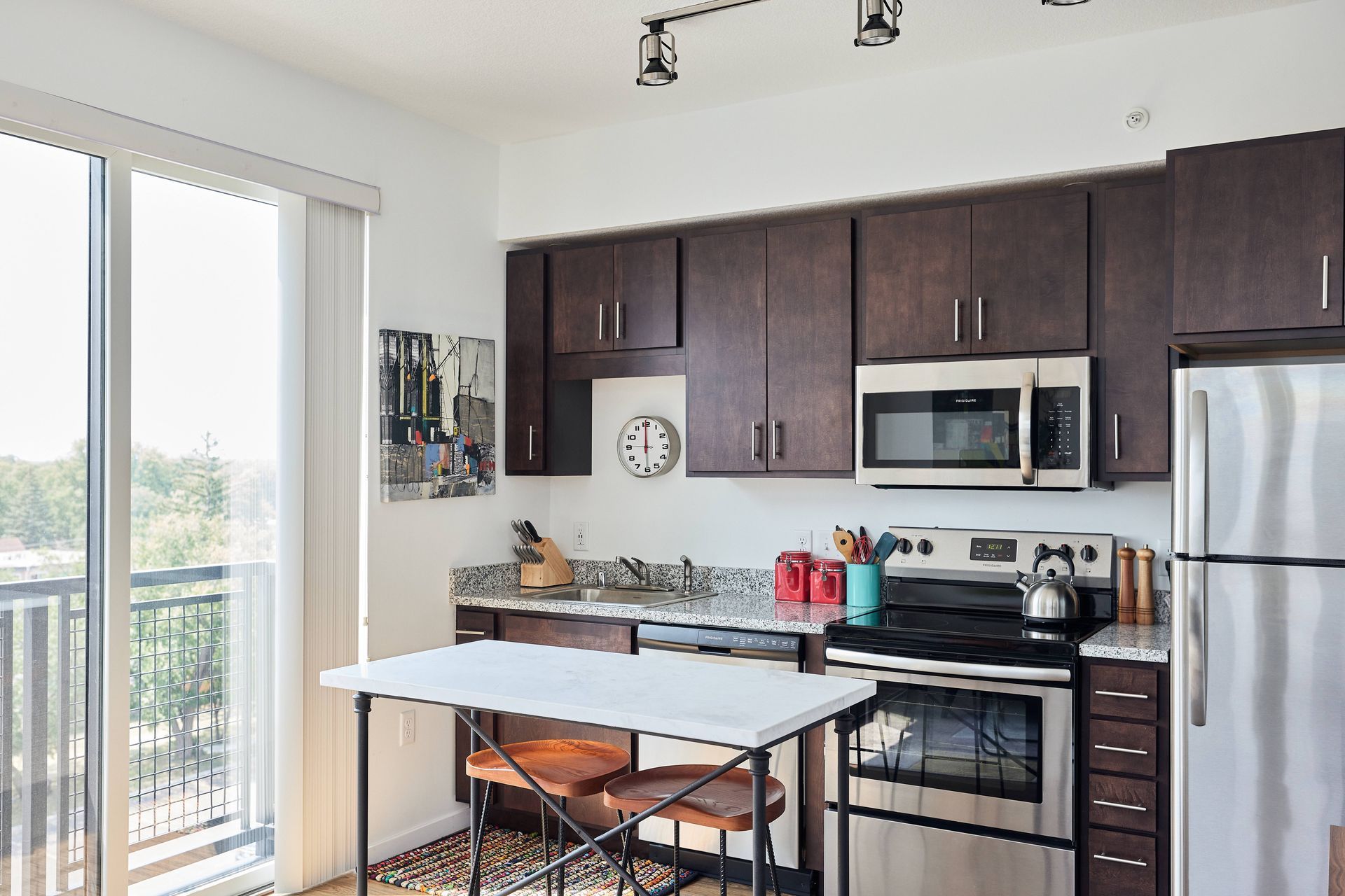 Modern kitchen with dark brown cabinets, stainless steel appliances, and a small breakfast bar at Southsider Apartments in Minneapolis, MN.