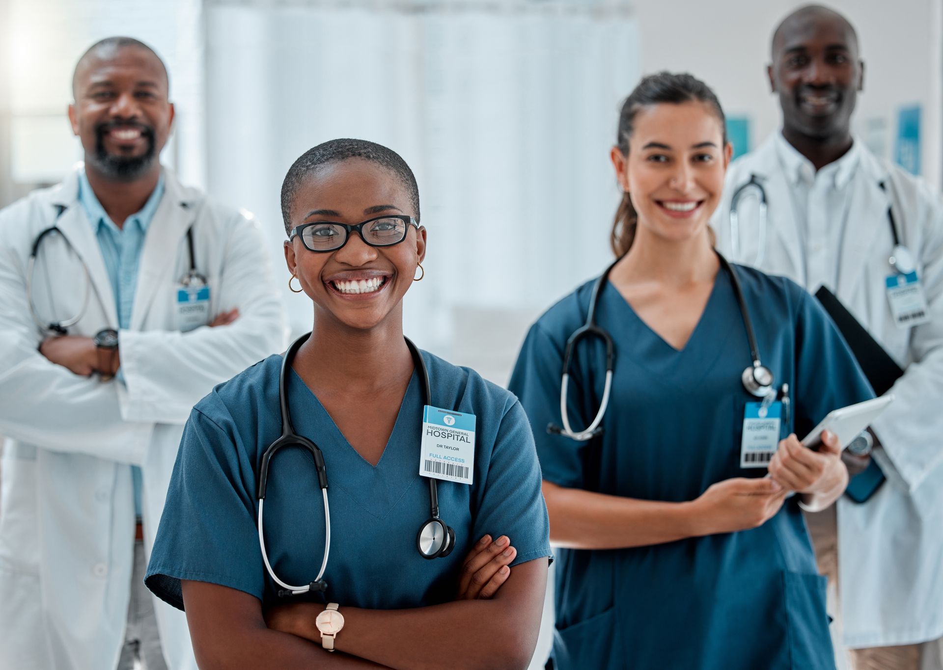 Group of healthcare workers in blue scrubs smiling in a hospital setting