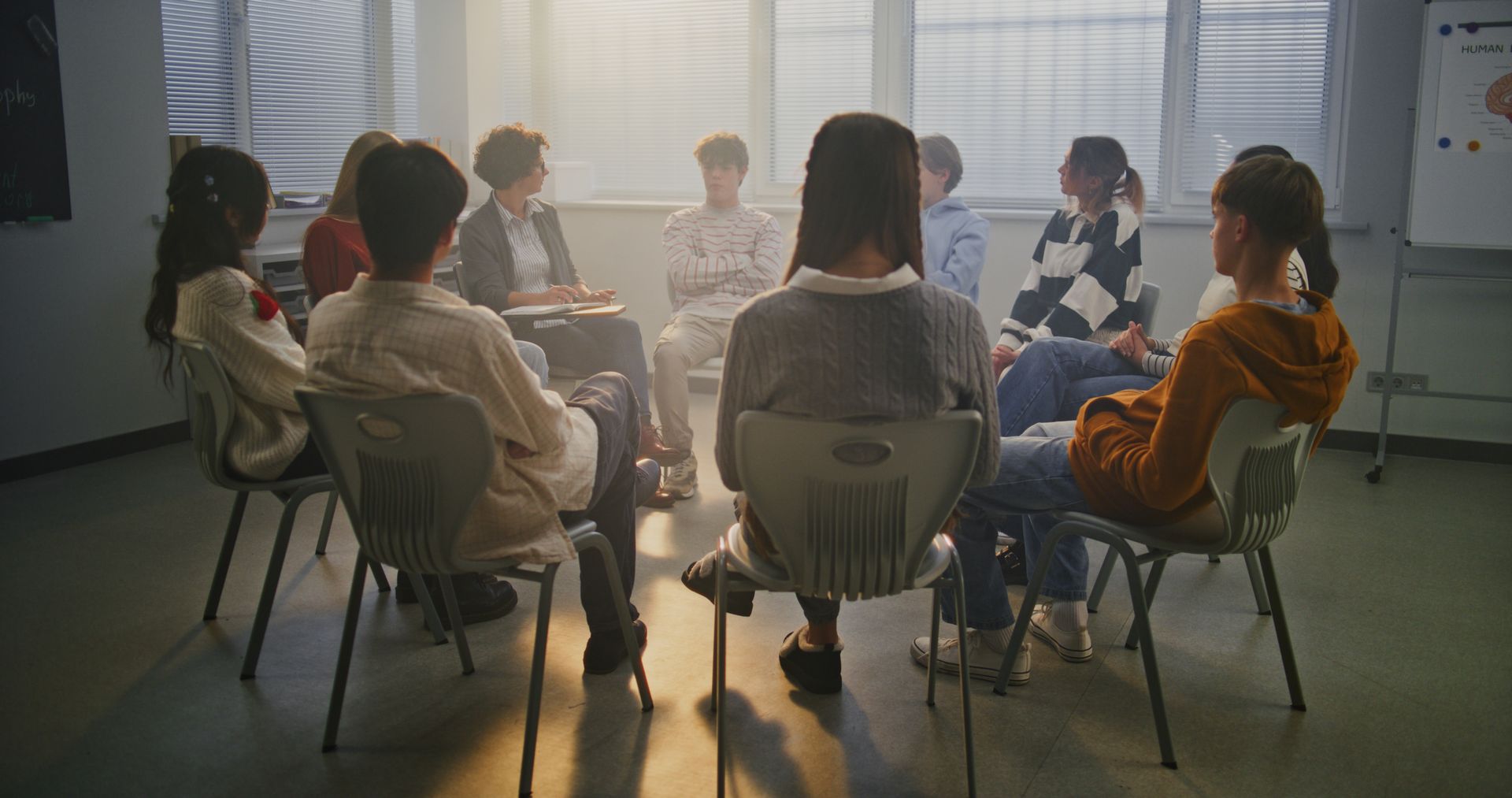 People seated in a circle during a meeting in a sunlit office room