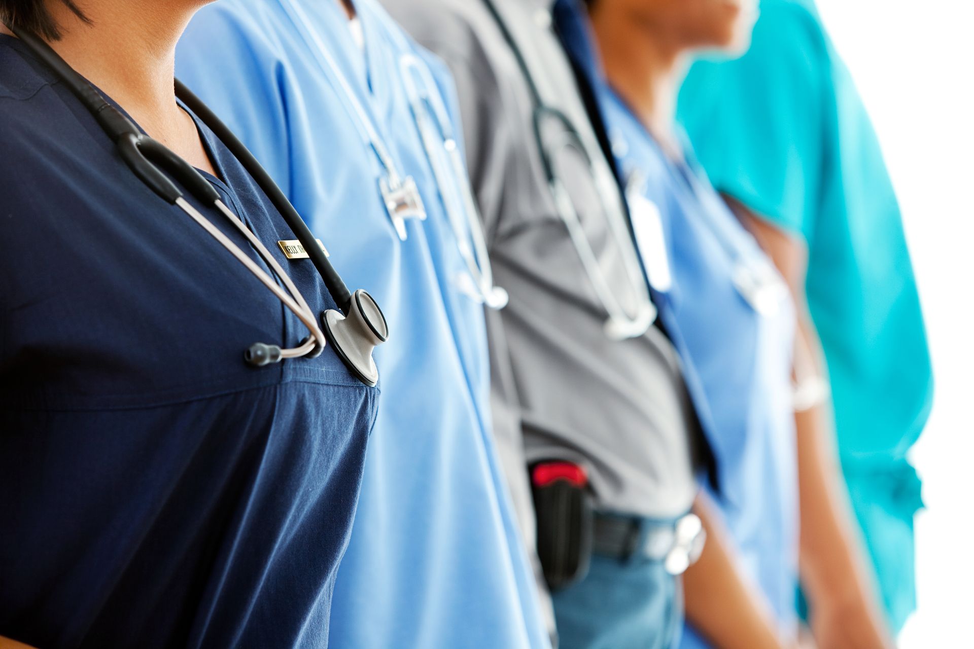 Healthcare workers in scrubs and stethoscopes standing in a row