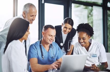 Healthcare team reviewing a laptop together in a bright office, smiling and collaborating