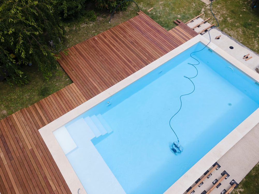 A Man Is Holding A Hose Next To A Pool — All Bright Pool Care In Laurieton, NSW

