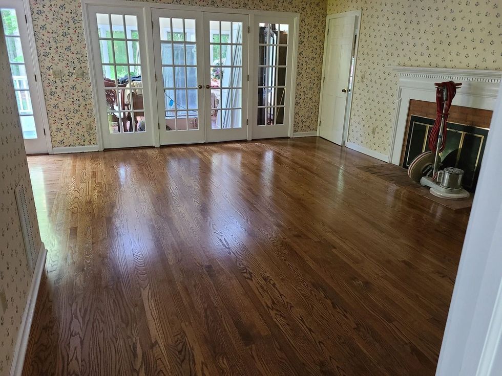 Empty living room with glossy hardwood floors, French doors, and a fireplace.