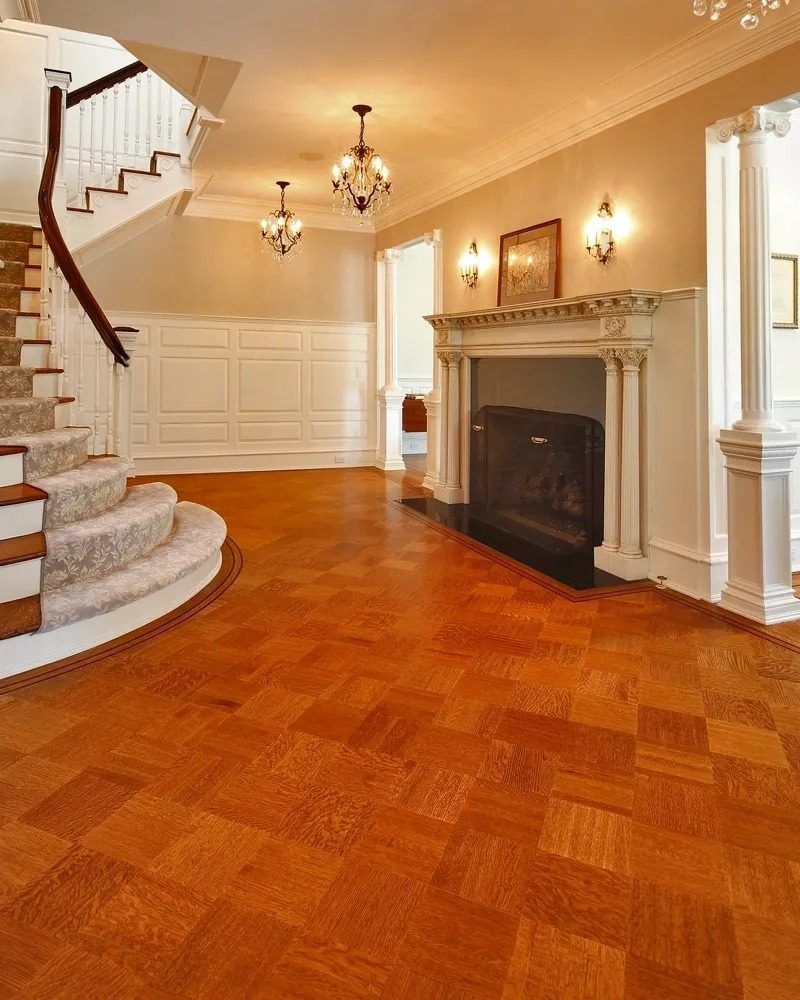 Elegant foyer with curved staircase, hardwood floor, and ornate fireplace mantel