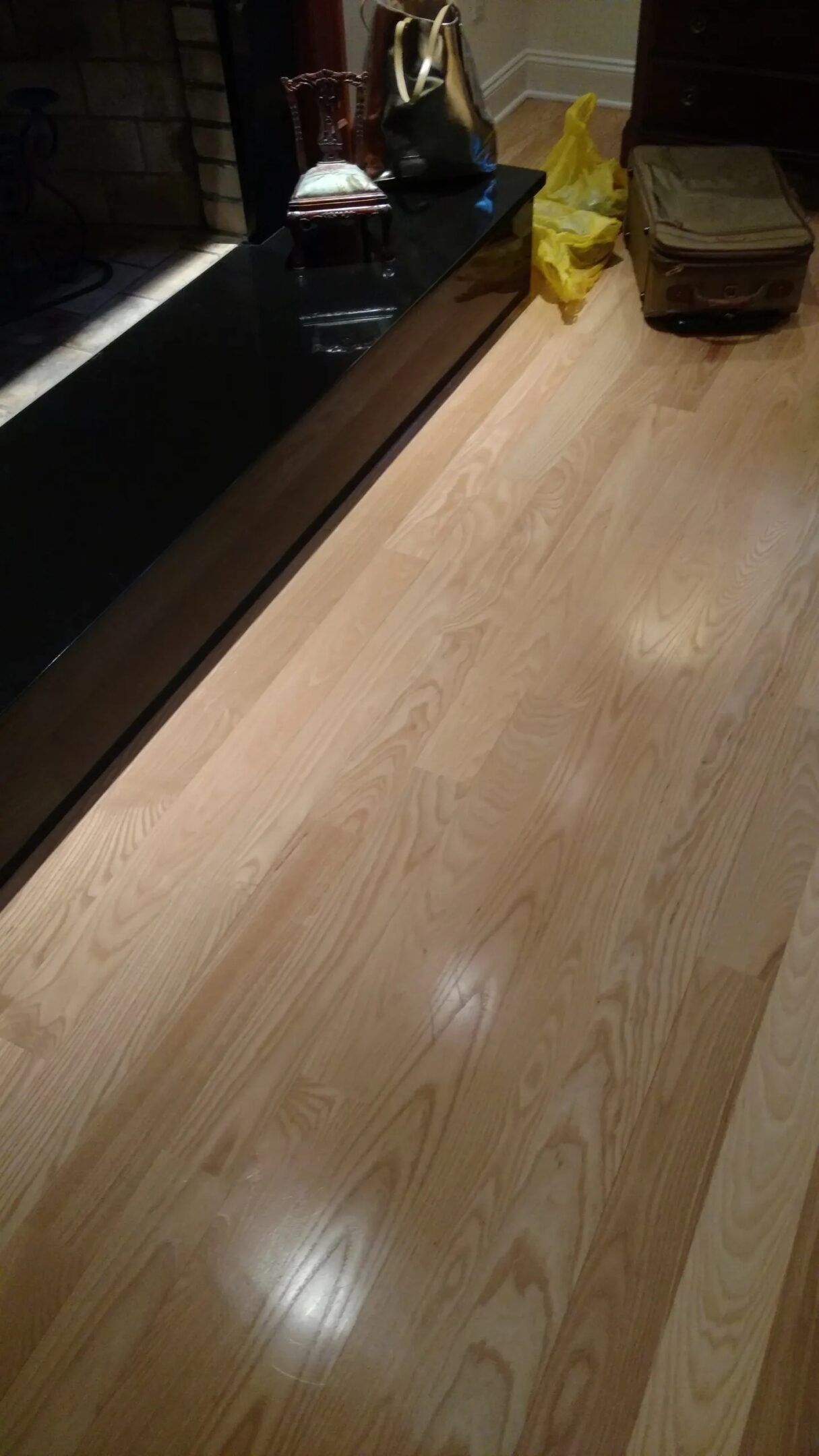 Wooden floor beside a dark counter with a yellow bag and a wicker basket in the background.