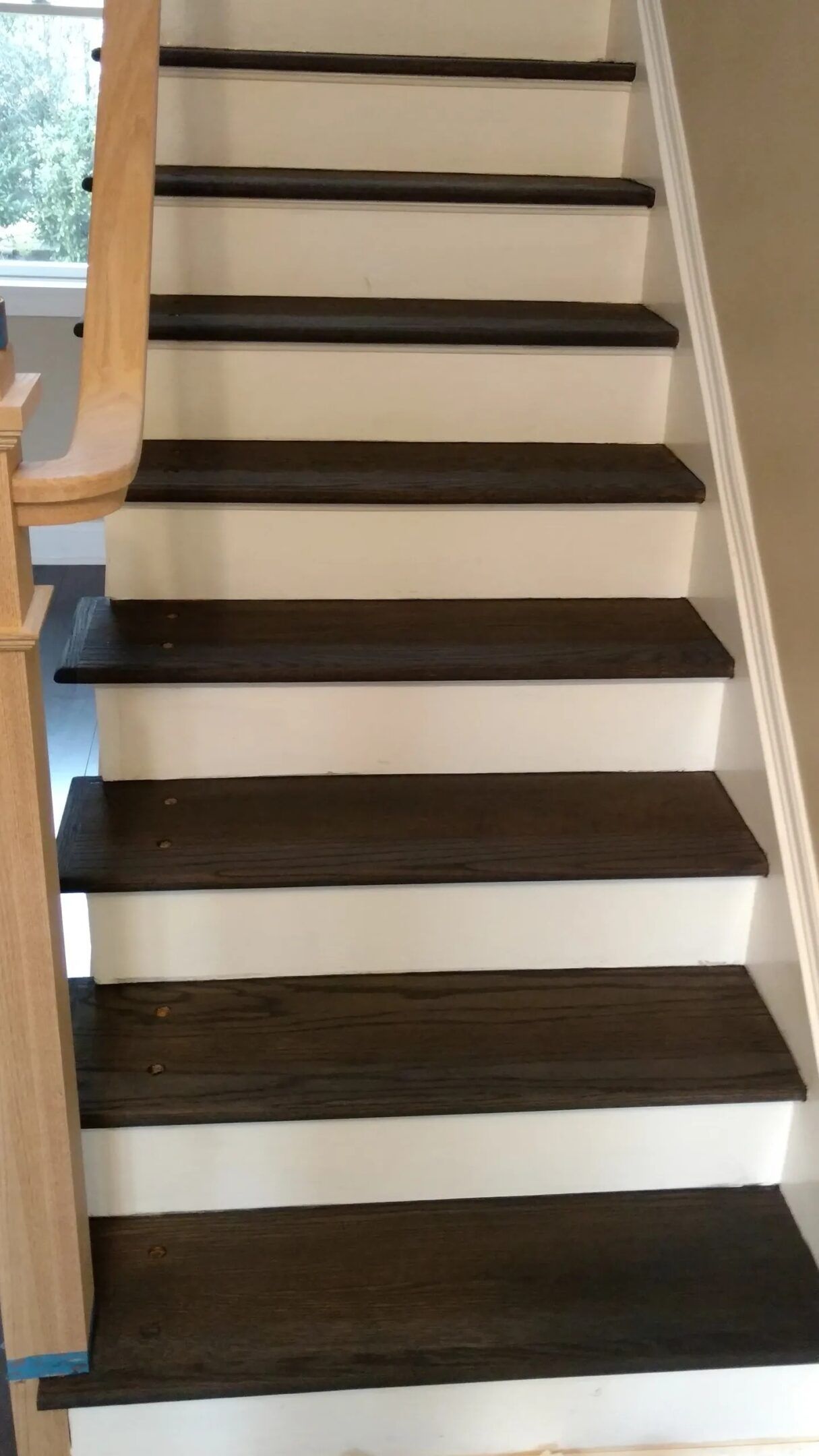 Indoor staircase with dark wooden steps, white risers, and a wooden handrail on the left.