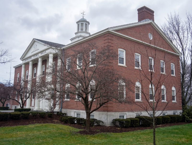 Red brick civic building with white columns and cupola on a cloudy day