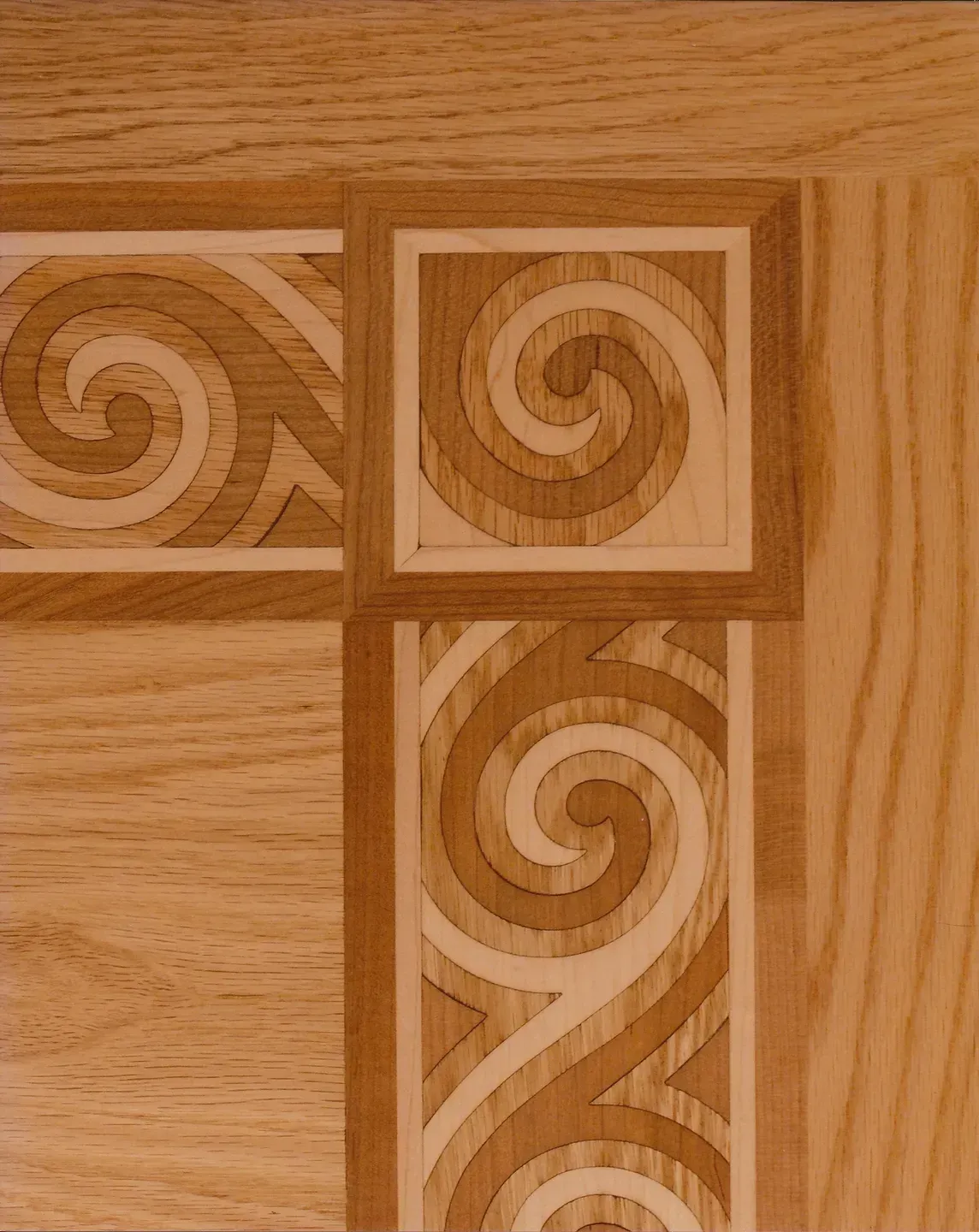 Close-up of light wood with carved geometric spiral tile patterns.