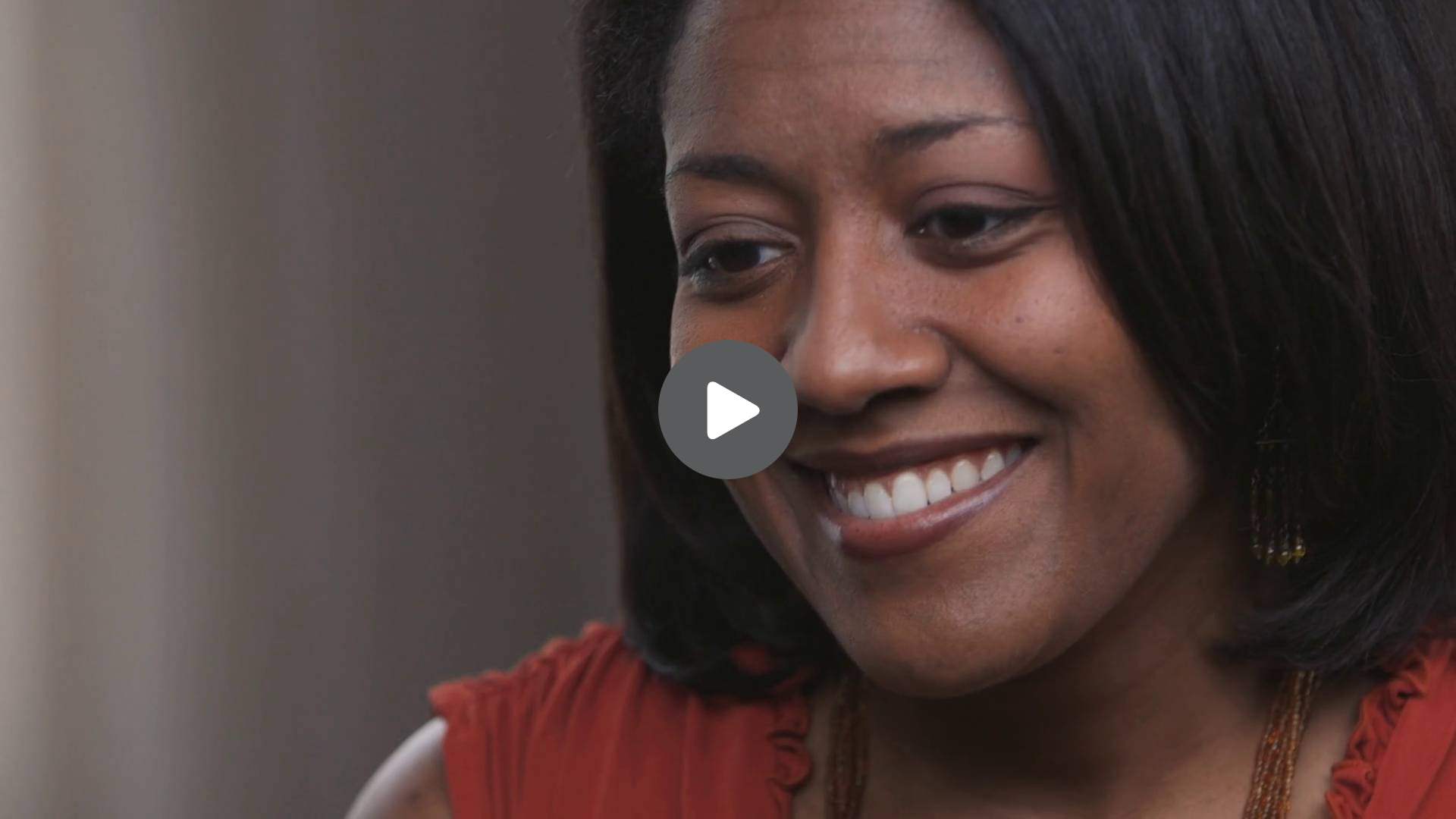 A woman is smiling with a play button on her face
