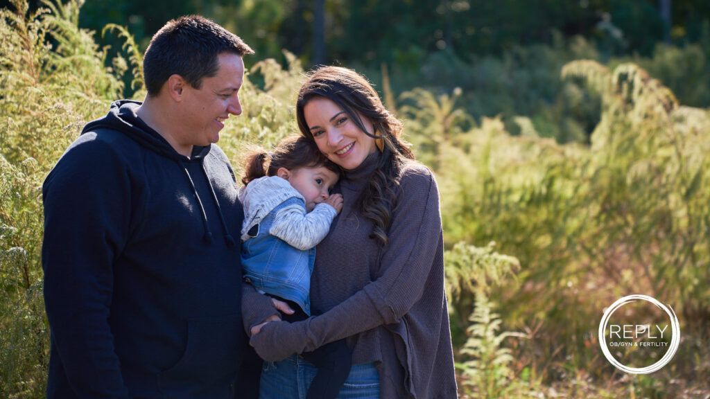 A man and woman are holding a baby in a field.