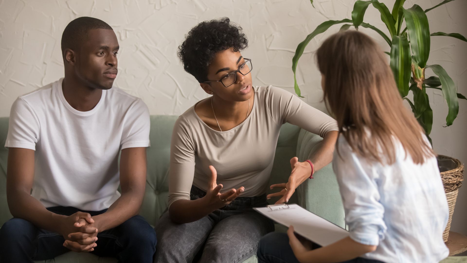 A man and a woman are sitting on a couch talking to a woman.