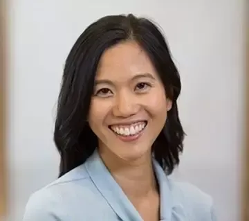 A woman in a blue shirt is smiling for the camera.