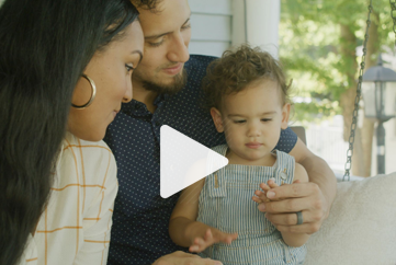 Play A man and woman are sitting on a porch with a baby.