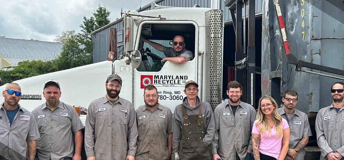 A group of ten people posing for a photo in front of a Maryland Rock Industries dump truck.