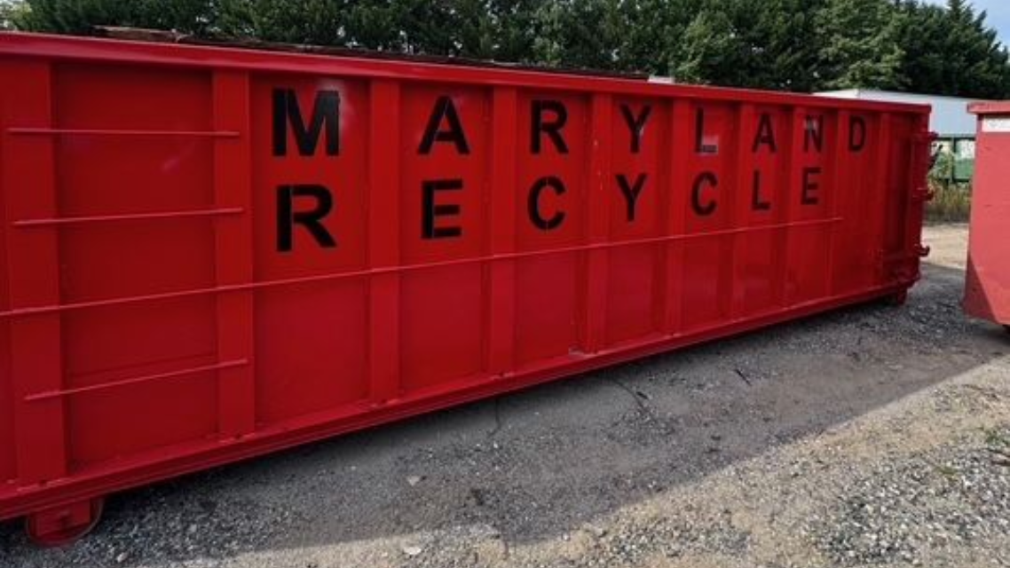 A long, red, metal roll-off dumpster featuring the words 