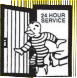24-hour service sign with a cartoon worker carrying equipment beside a striped storefront