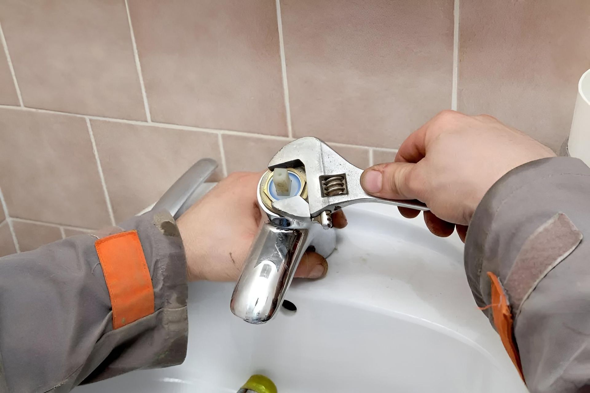 Person is Fixing a Sink Faucet With a Wrench — Wet & Dry Plumbing & Gas in Highfields, QLD