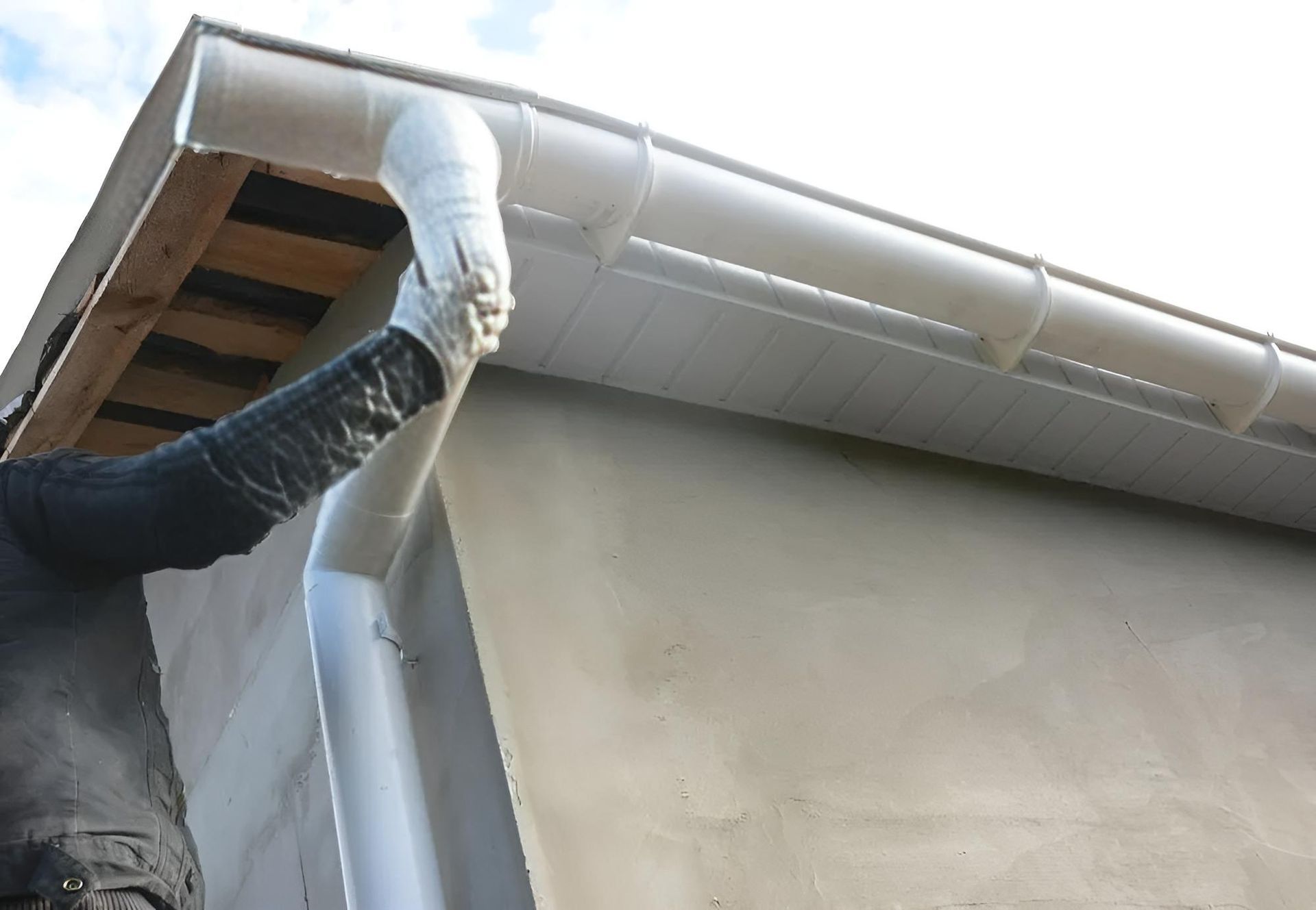 Man is Installing a Gutter on the Side of a House — Wet & Dry Plumbing & Gas in Newtown, QLD
