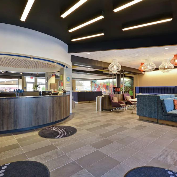 Hotel lobby with check-in desk, seating area with sofa, and decorative lighting.