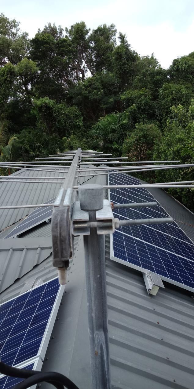 A Roof With Solar Panels On It And Trees In The Background — Laurence Capocchi Antenna Guy In Trinity Beach, QLD