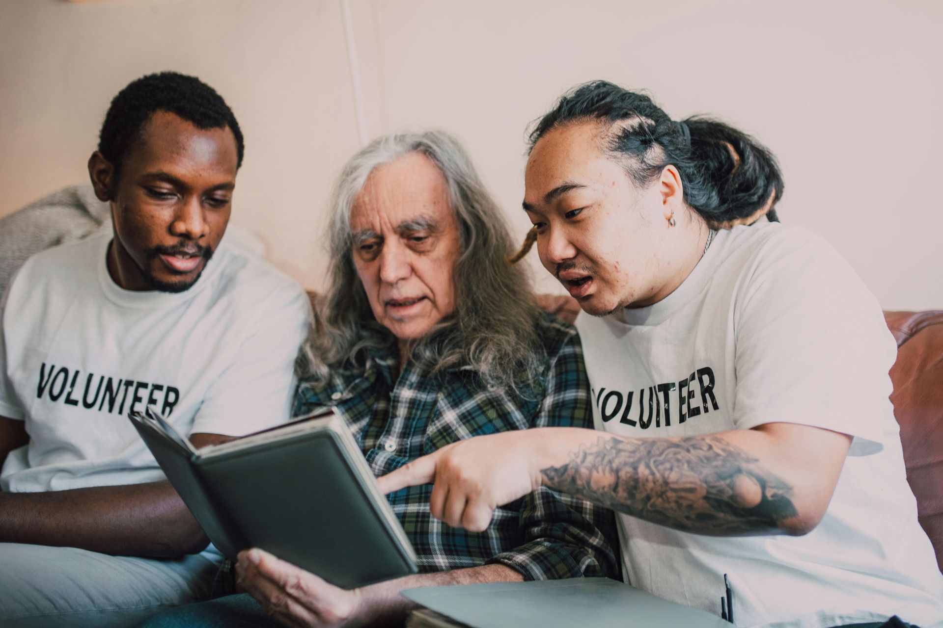 Three people looking at a book together. Two wearing 