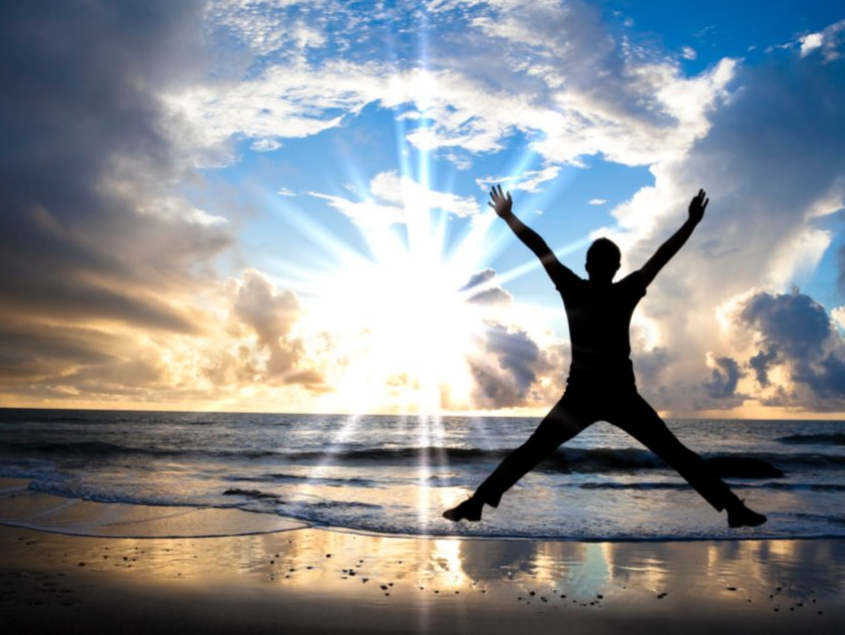 A silhouette of a person jumping in the air on a beach