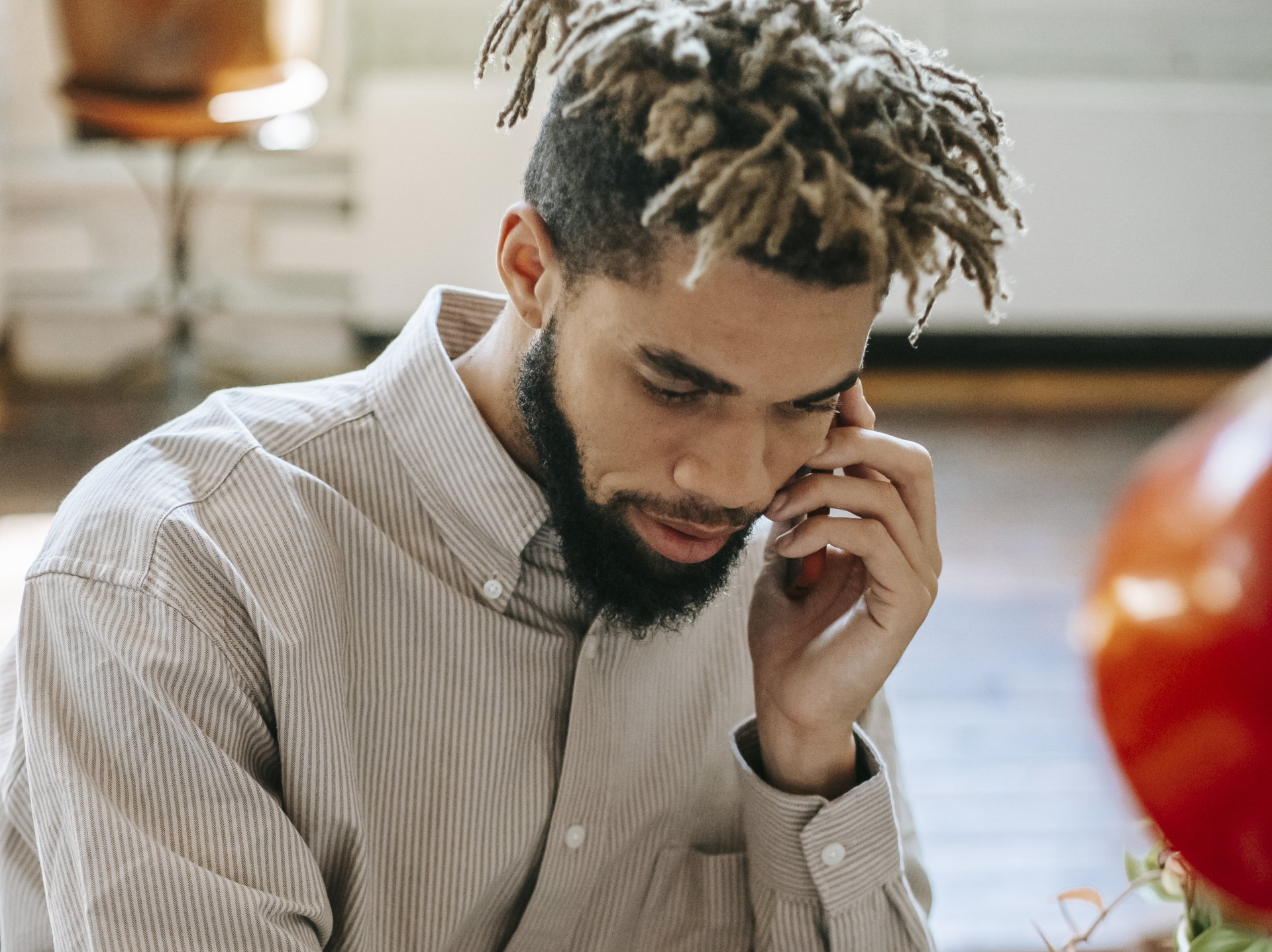 A man with dreadlocks and a beard is talking on a cell phone.