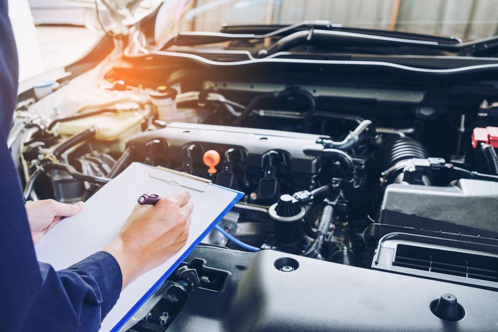 A Mechanic is Writing While Looking at the Engine of a Car — Jon Wilson Mechanical in Eaglehawk, VIC