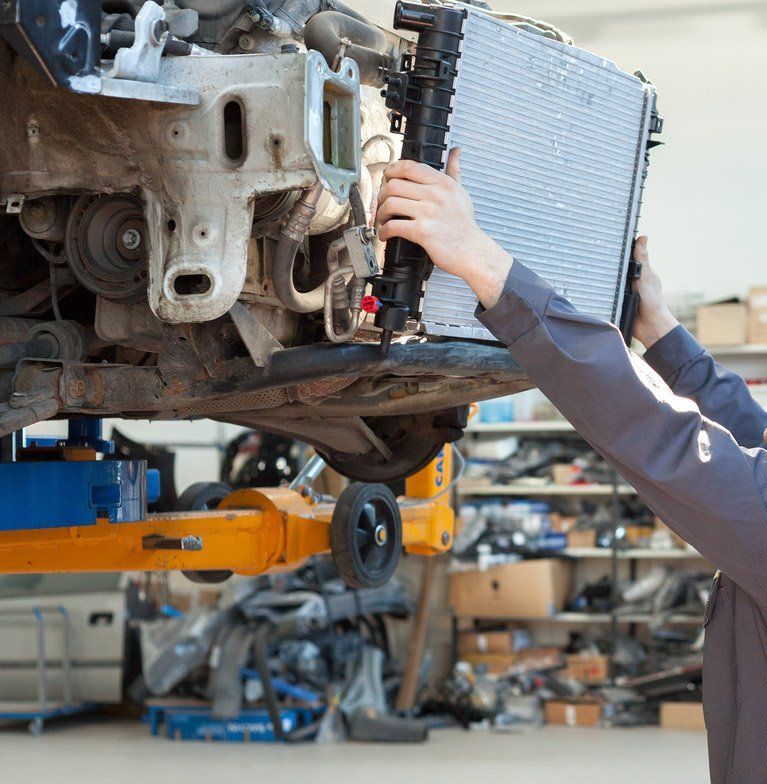 A man is holding a radiator while working on a car — Jon Wilson Mechanical in Eaglehawk, VIC