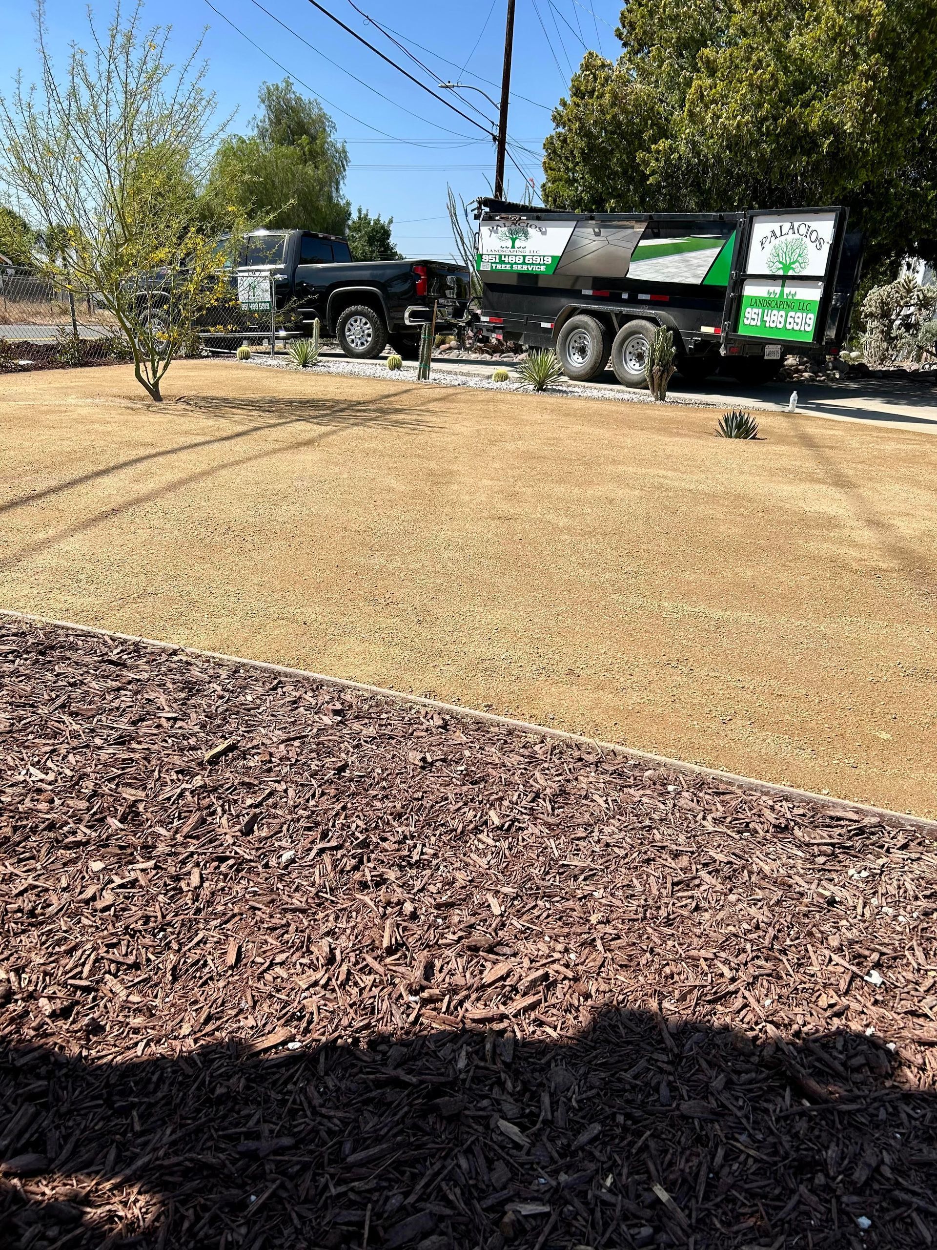 A truck is parked in a yard next to a pile of mulch.